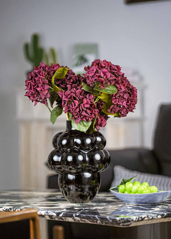 Crimson velvet artificial hydrangea bouquet in black sculptural vase for elegant home decor.