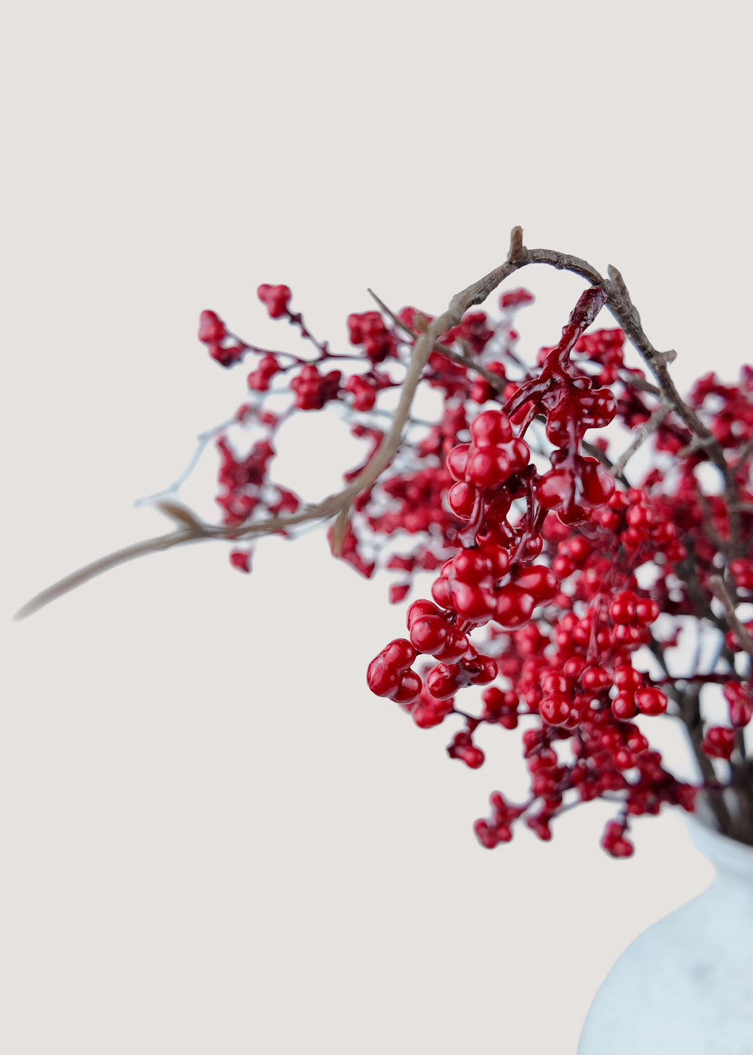 Close-up of lifelike faux red berries with natural stems