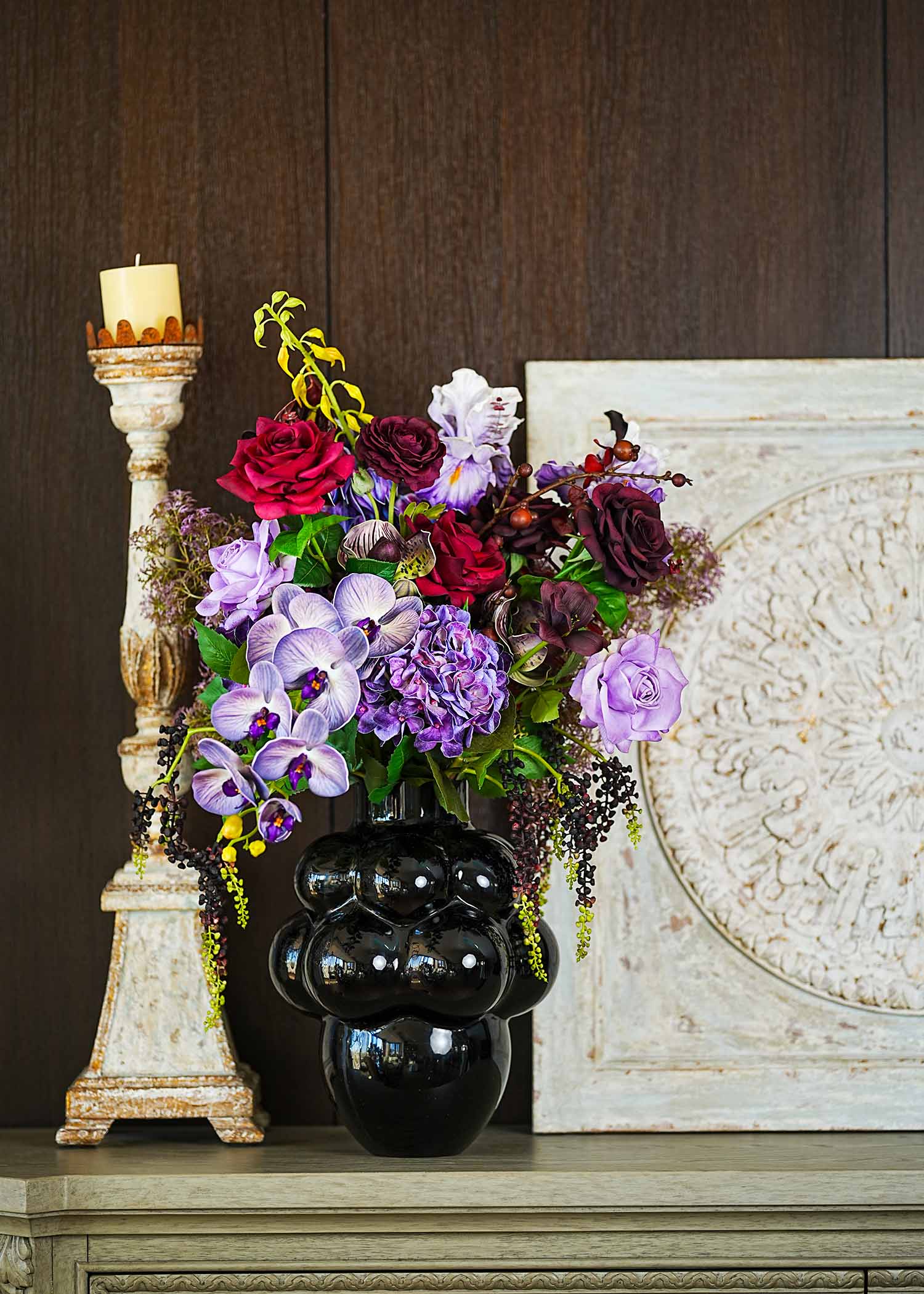 Elegant purple and red faux floral arrangement with hydrangeas, roses, and orchids creating a luxurious living room atmosphere.