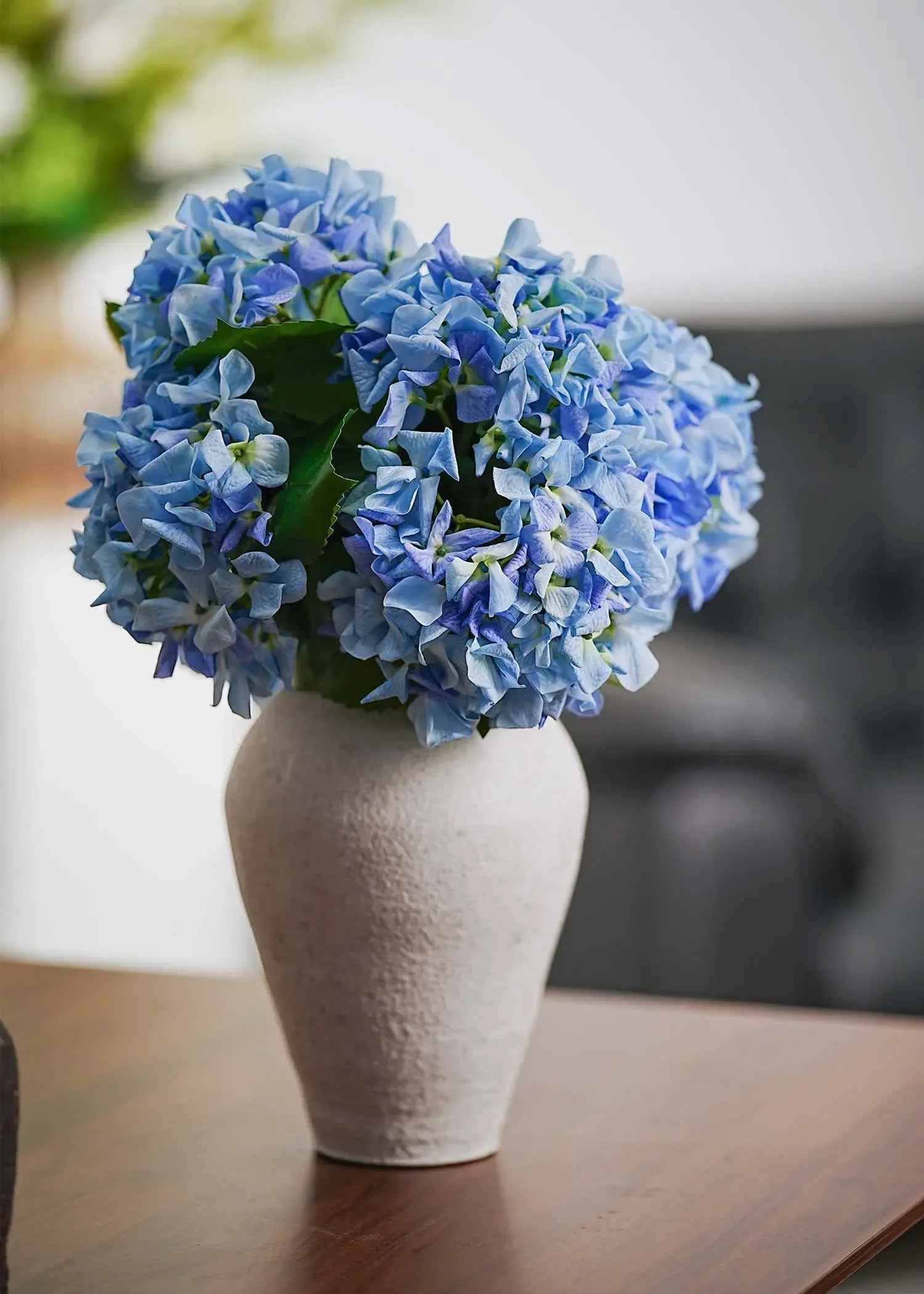 Everblooma sky blue artificial hydrangeas in white ceramic vase, side angle showcasing realistic faux flower texture