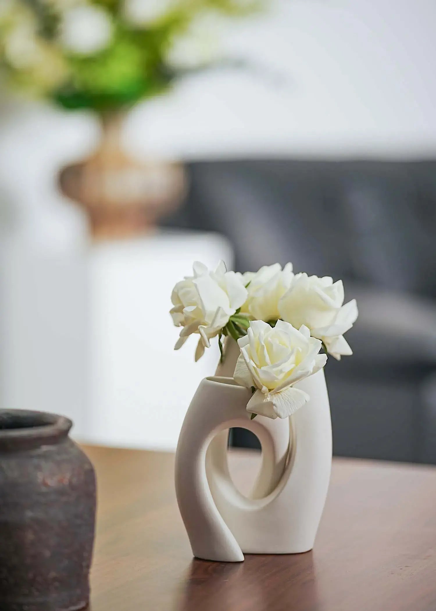 Elegant white rose bouquet in modern sculptural vase on wooden table, contemporary interior accent by Everblooma