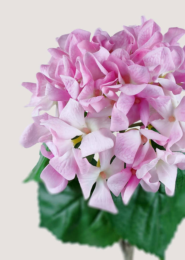 Close-up detail of pink faux hydrangea petals and realistic root, showcasing lifelike texture.