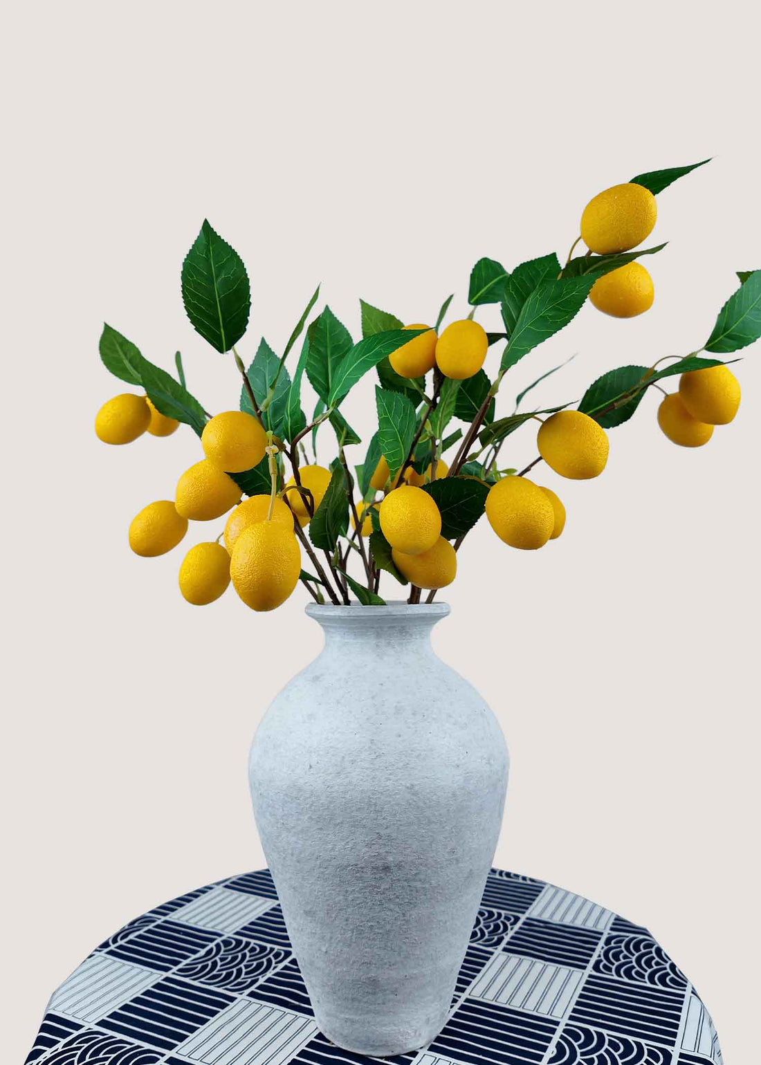 Artificial lemon branches with yellow fruits in white vase
