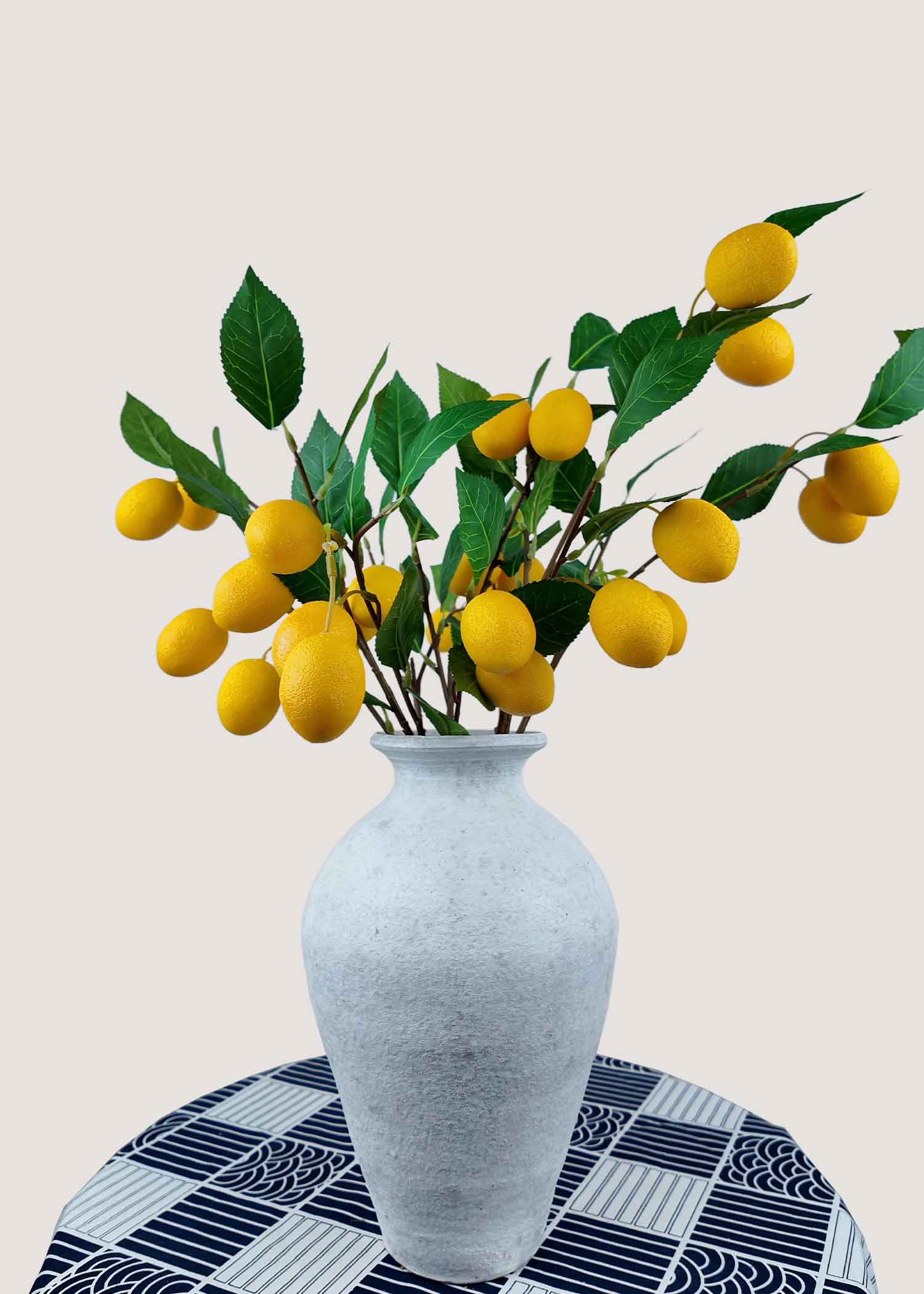 Artificial lemon branches with yellow fruits in white vase