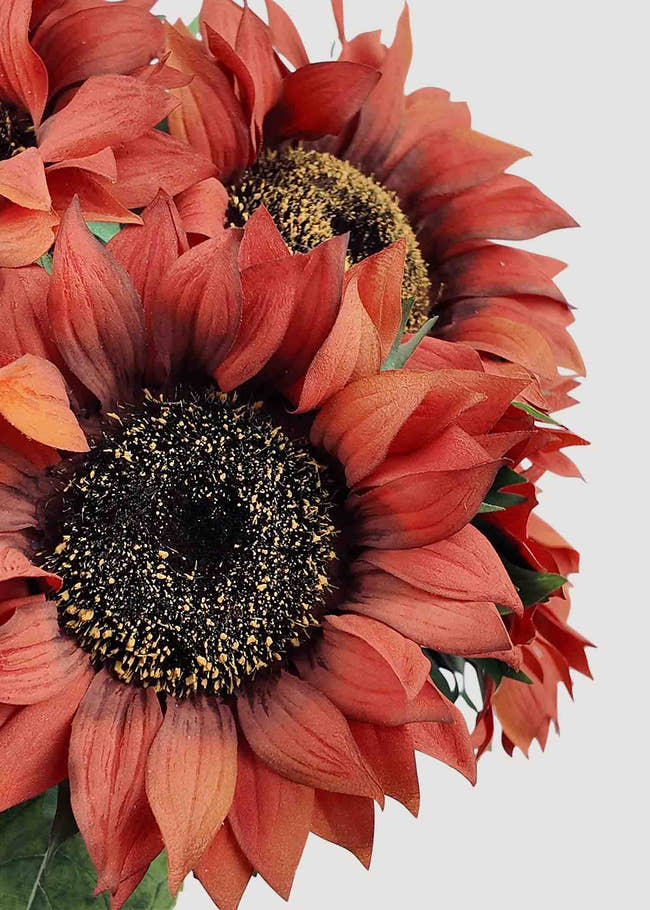 Closeup of lifelike burnt orange artificial sunflower blooms