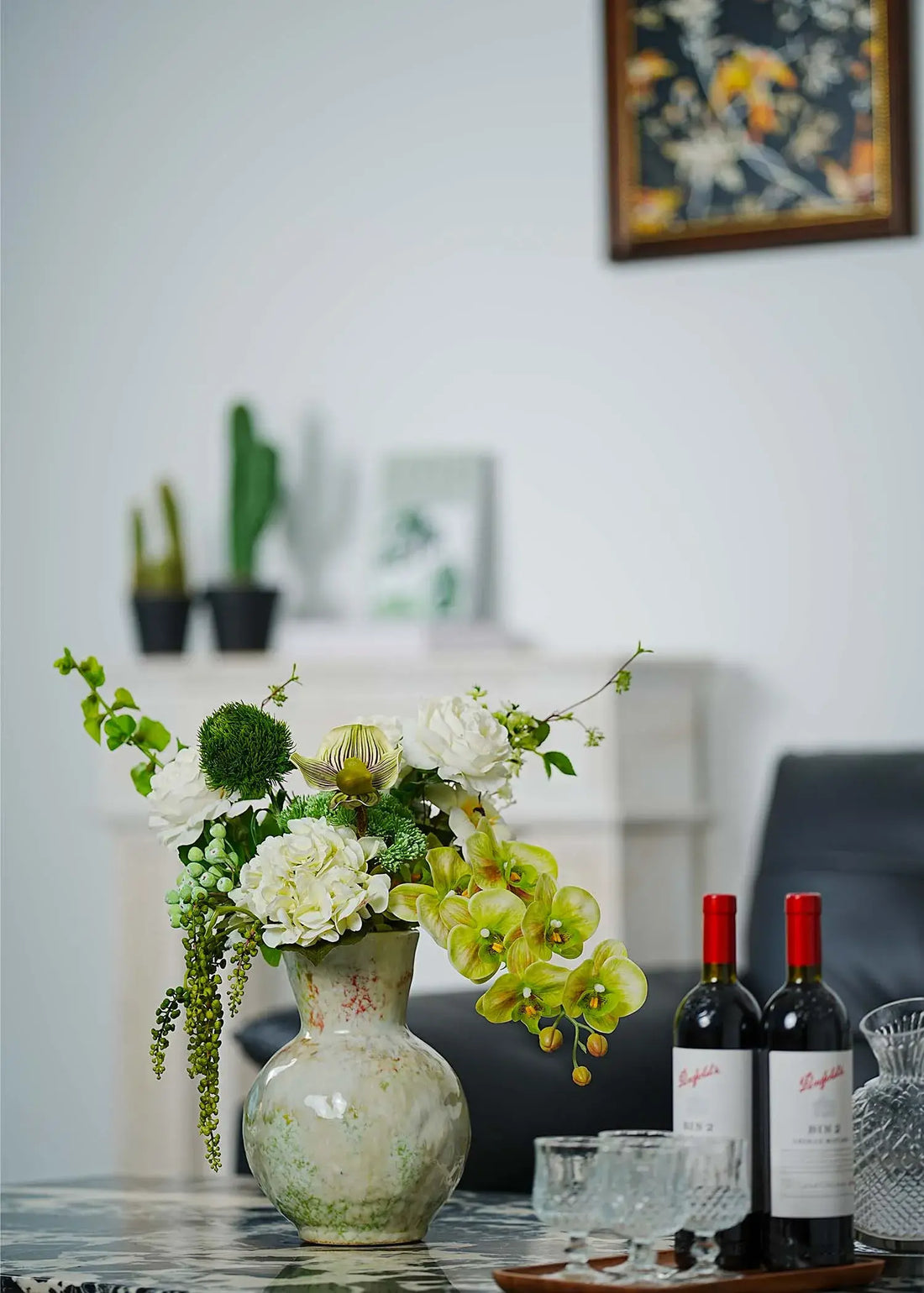 Deluxe white and green faux floral arrangement with orchids, roses, and hydrangeas styled on a dining table with wine bottles – Everblooma home décor flowers