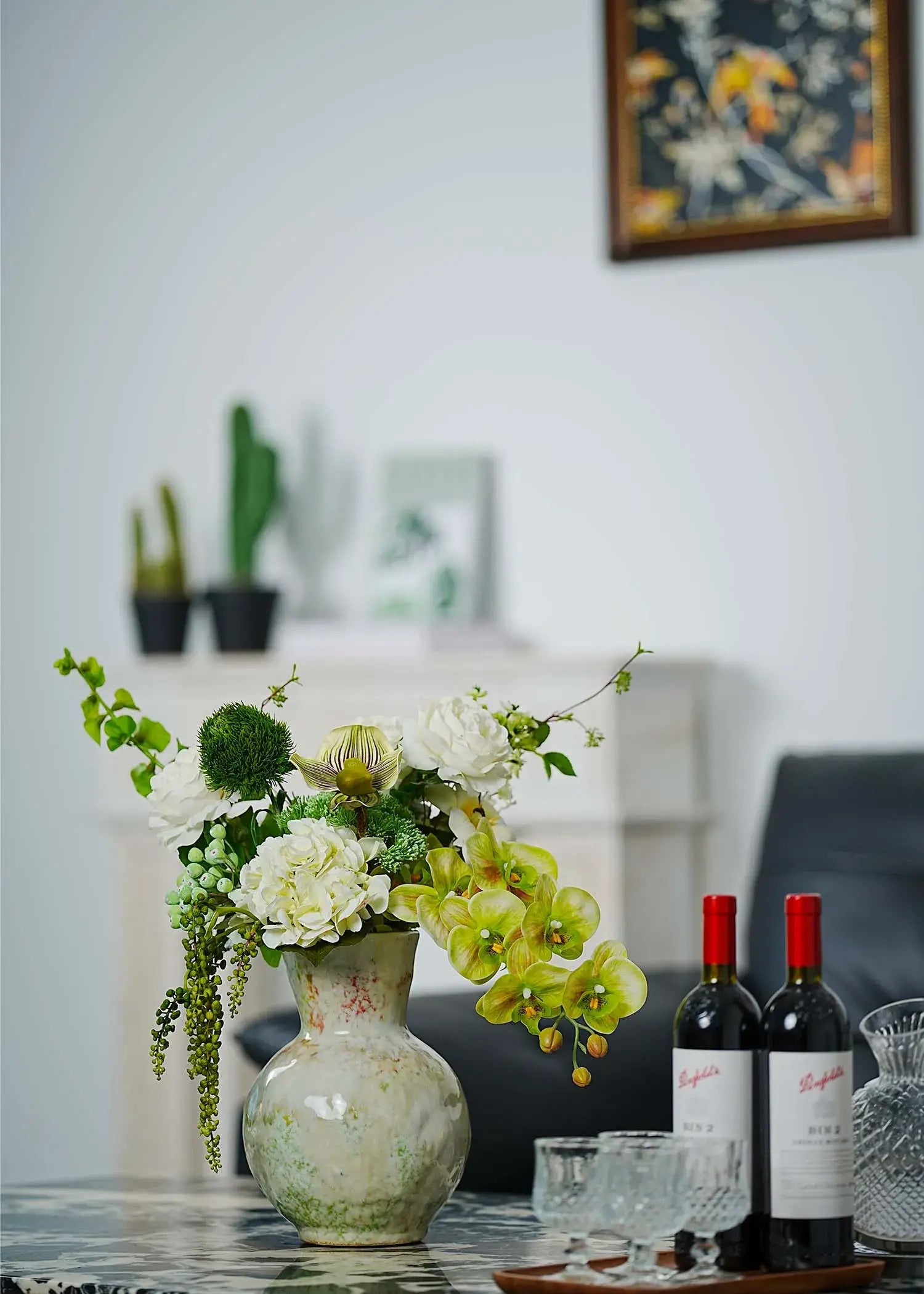 Deluxe white and green faux floral arrangement with orchids, roses, and hydrangeas styled on a dining table with wine bottles – Everblooma home décor flowers