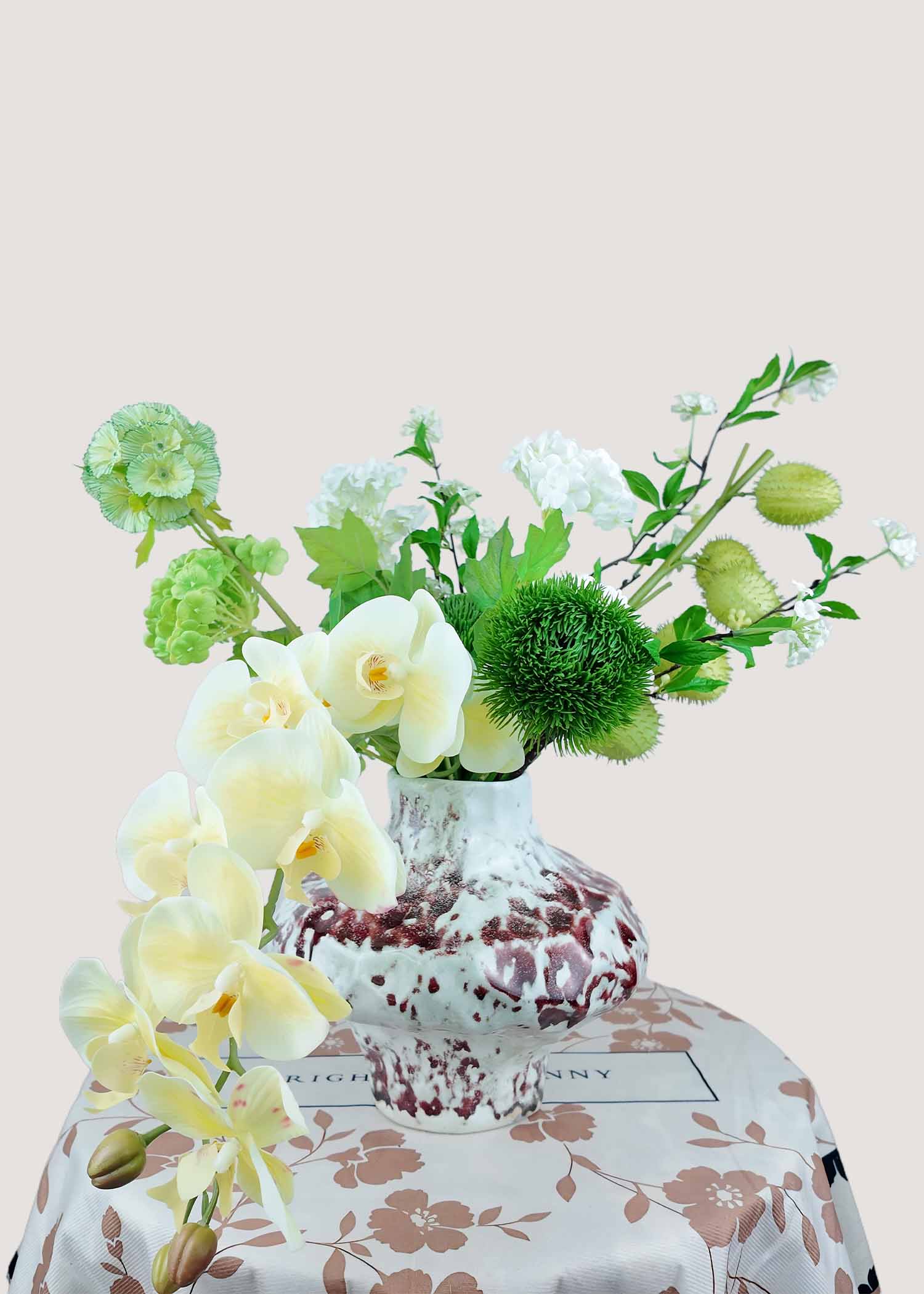 Cream orchid faux floral arrangement with green textured accents in artistic vase – luxury artificial flowers centerpiece.