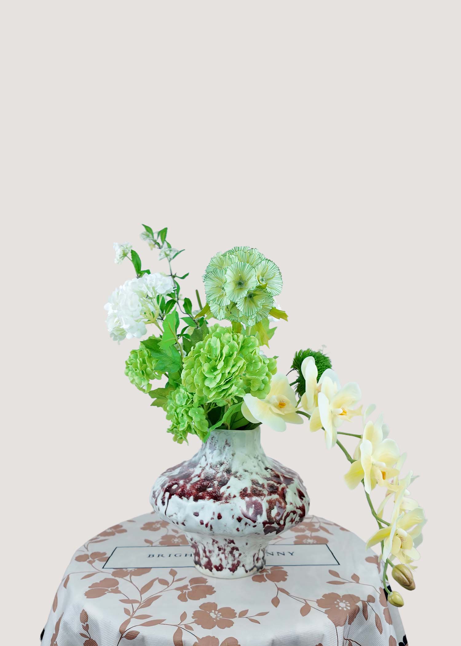 Right angle of elegant orchid and green pod faux flower arrangement.