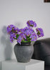 Lavender artificial hydrangeas bouquet in matte black vase on white side table, minimalist living room decoration