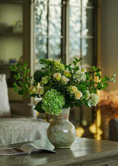 Everblooma Real Touch faux floral arrangement featuring green hydrangea and white roses in a ceramic vase, styled in a cozy living room.