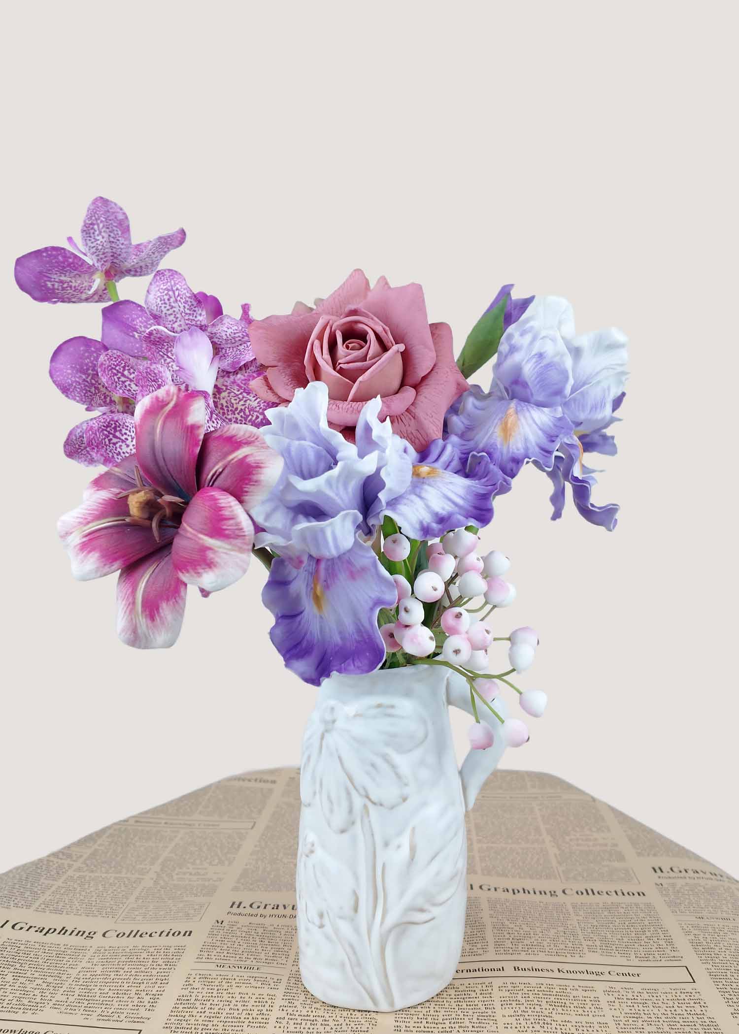 Small faux floral arrangement with mauve rose, purple orchid, iris blooms, and berries in vase.