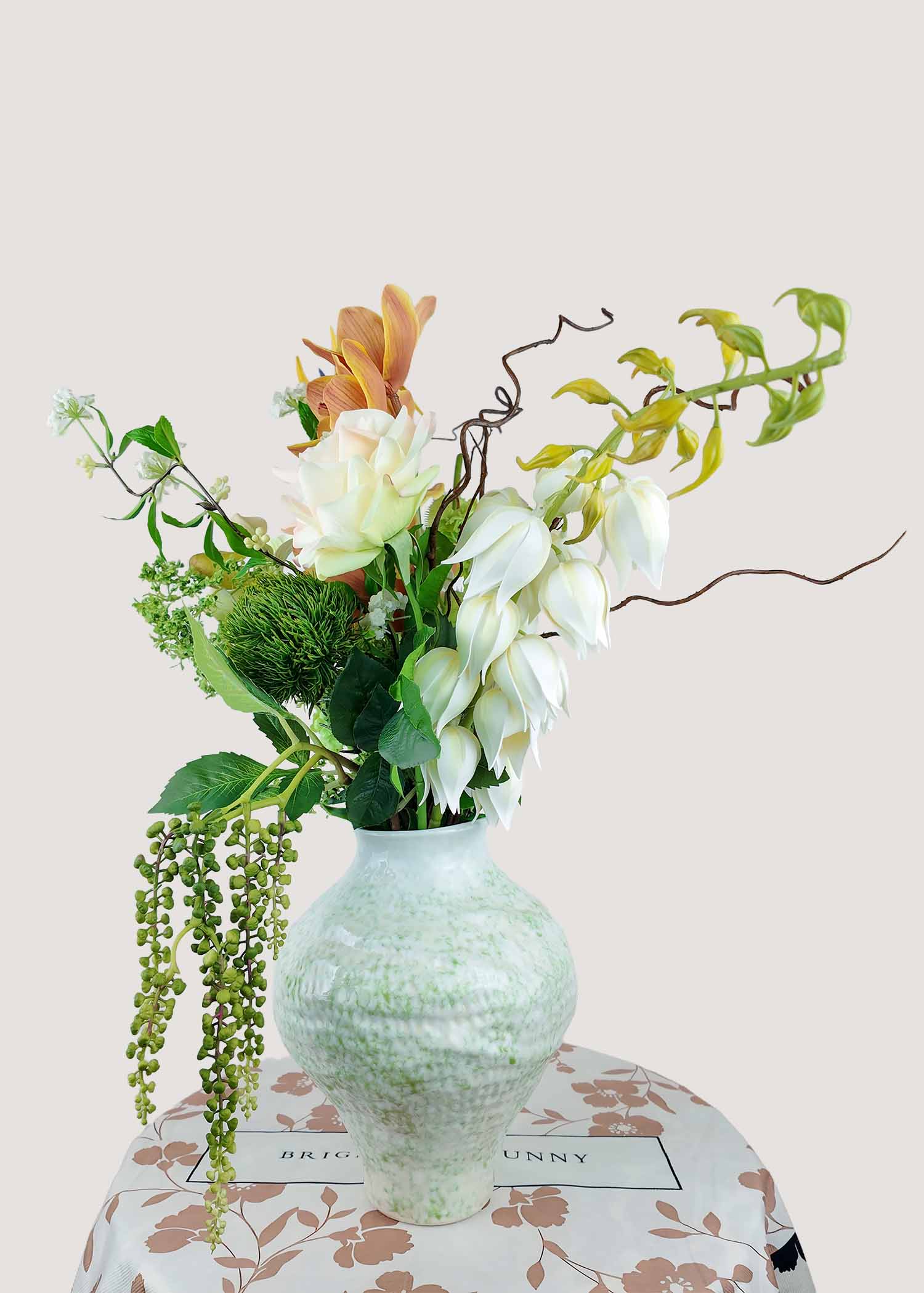 Right angle of exotic artificial floral arrangement featuring orchids, pokeweed berries, and hydrangea.