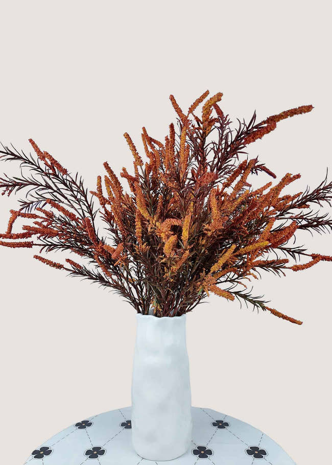 Autumn orange artificial flower bouquet with rustic faux branches in vase