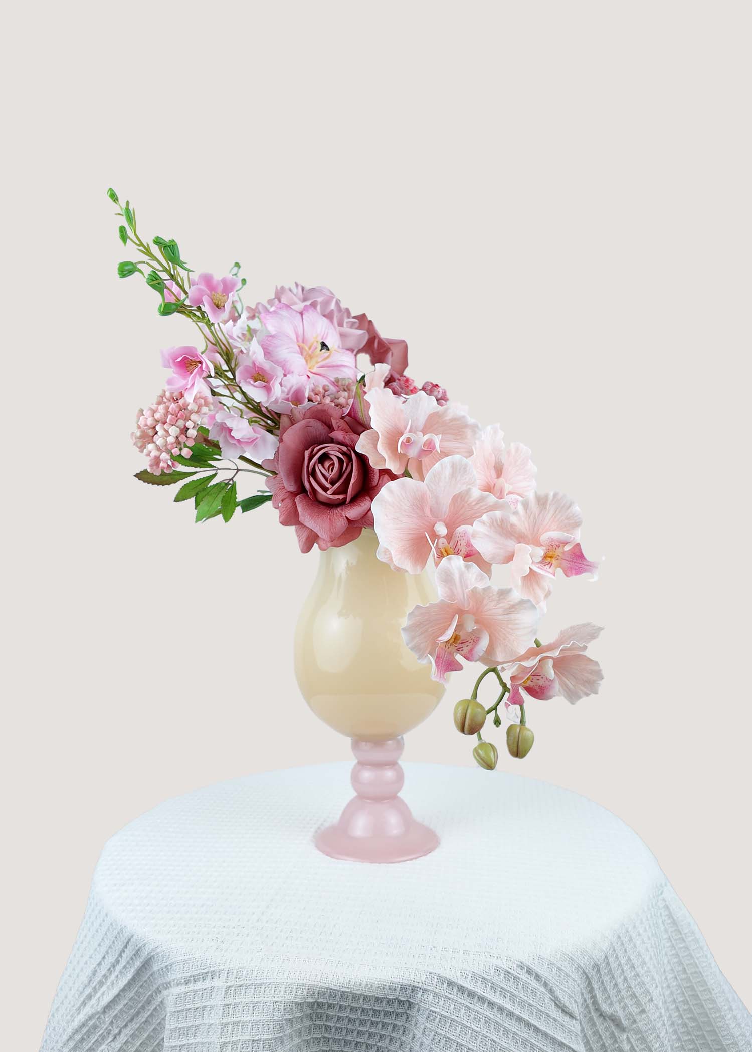 Side view of artificial pink rose and orchid arrangement in decorative vase, left angle