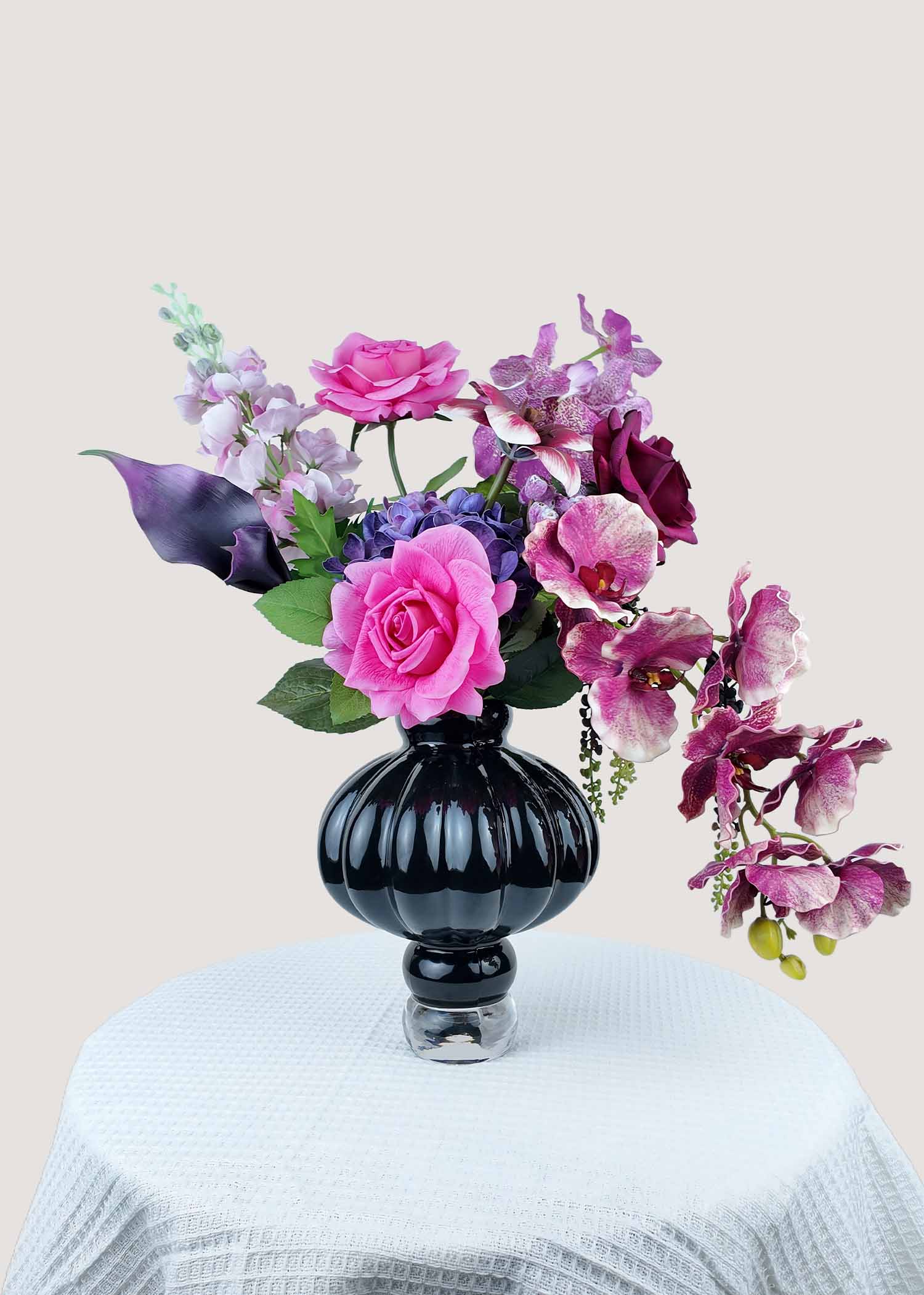 Main view of pink and purple artificial rose and orchid arrangement in black vase