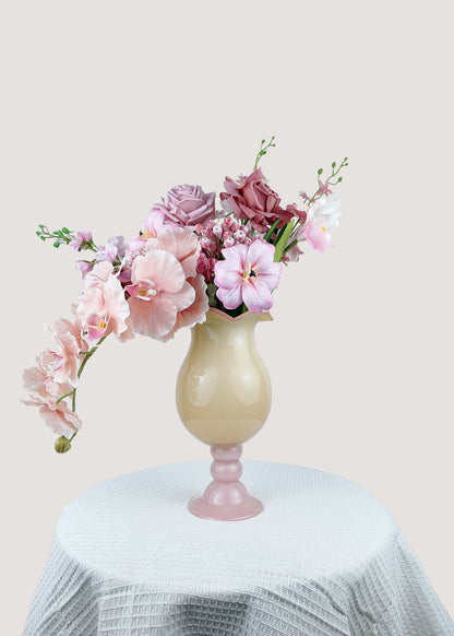 Front view of pink artificial flower arrangement with roses and orchids in a beige vase