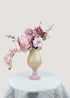 Front view of pink artificial flower arrangement with roses and orchids in a beige vase
