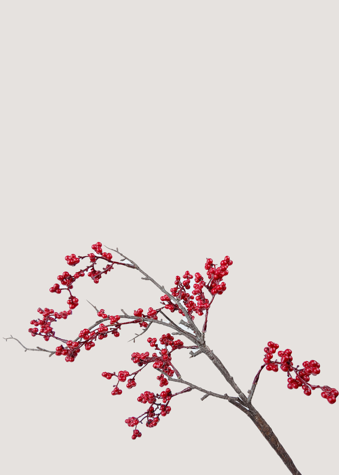 Close-up detail of realistic faux red berries on artificial branch