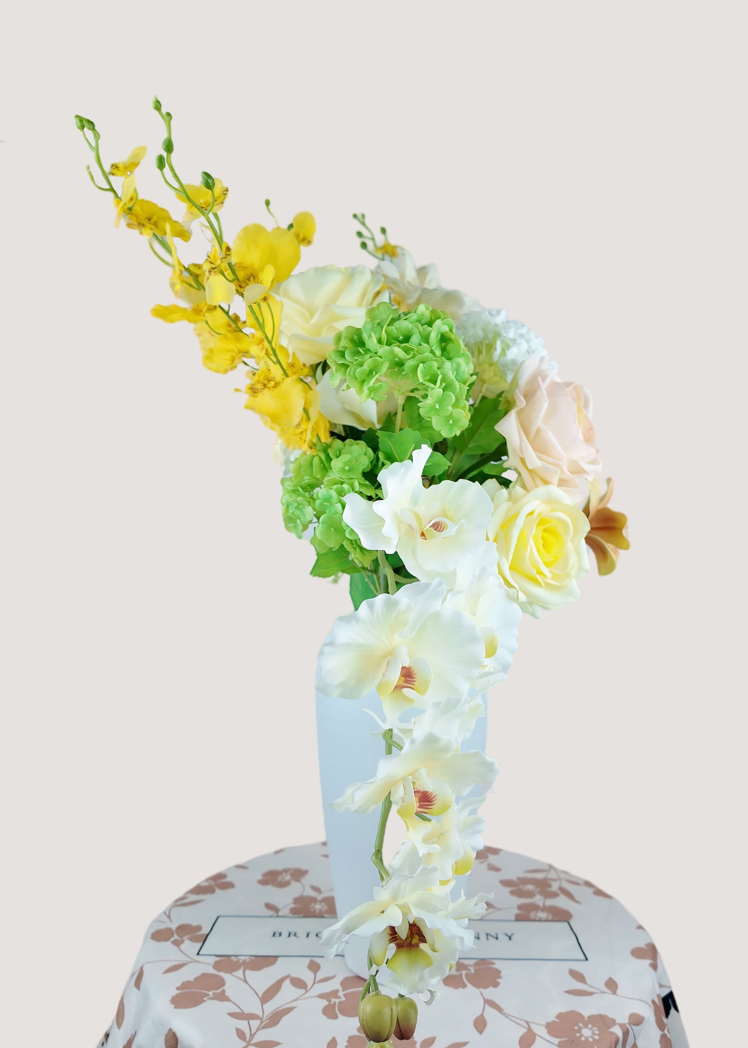 Side view of faux orchid rose centerpiece in cream and yellow
