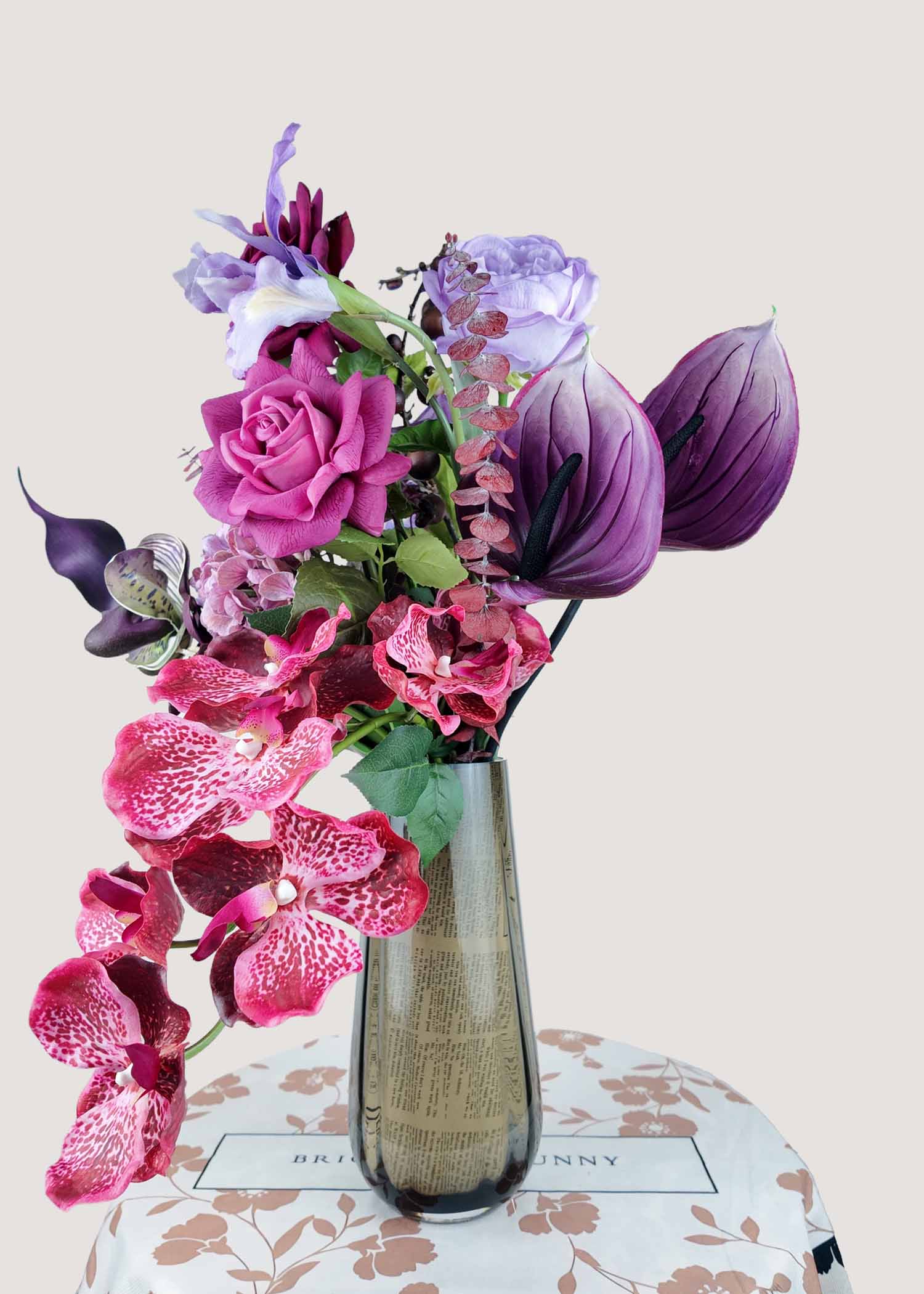 Faux orchid and rose bouquet in burgundy and lilac tones